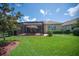 Backyard featuring lush green lawn, mature trees, and a cozy screened-in patio at 2425 Laurel Glen Dr, Lakeland, FL 33803