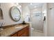 Bathroom with granite countertops, a round mirror, and a glass-enclosed shower at 2425 Laurel Glen Dr, Lakeland, FL 33803