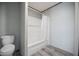 This bathroom features a white tub with shower, white toilet and neutral wall and floor coverings at 246 Quail Run, Frostproof, FL 33843