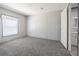 A neutral carpeted bedroom features a window with blinds, neutral walls and door to the bathroom at 246 Quail Run, Frostproof, FL 33843