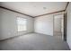 A neutral carpeted bedroom features a window with blinds, neutral walls and door to another room at 246 Quail Run, Frostproof, FL 33843