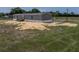 View of the side of this single-story home with gray siding and a dark roof with a yard full of grass and dirt at 246 Quail Run, Frostproof, FL 33843