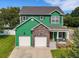 Inviting two-story green home featuring a stone facade, covered porch, and an attached two-car garage at 2731 Coventry Ave, Lakeland, FL 33803