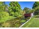 Scenic backyard canal view with lush greenery, mature trees, and a red corrugated metal shelter at 2757 Pine Acres Dr, Lake Wales, FL 33898