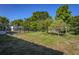 Large grassy backyard enclosed by a black fence and featuring mature trees, bushes, and a storage shed at 2757 Pine Acres Dr, Lake Wales, FL 33898