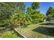 Landscaped backyard with lush green grass, trees, retaining wall, and canal views at 2757 Pine Acres Dr, Lake Wales, FL 33898