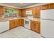 Traditional kitchen with wood cabinets, neutral countertops, white appliances, and a garden window at 2757 Pine Acres Dr, Lake Wales, FL 33898