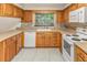 Well-lit kitchen with wood cabinetry, white appliances, and a garden window offering a pleasant view at 2757 Pine Acres Dr, Lake Wales, FL 33898