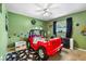 Bedroom features unique red racecar bed, green walls, ceiling fan, and natural light at 2810 Gary Ln, Lakeland, FL 33812