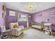 Bedroom boasts purple walls, chair, golden crib, changing table, and window view at 2810 Gary Ln, Lakeland, FL 33812