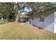 View of a backyard with a covered deck, mature trees, and lush grass at 2920 Audie Combee Rd, Lakeland, FL 33801