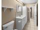 Well-lit bathroom featuring a white sink, toilet, and storage cabinet with neutral wall and floor tiles at 2920 Audie Combee Rd, Lakeland, FL 33801