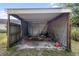 View of partially enclosed carport with concrete floor and a couple of chairs at 2920 Audie Combee Rd, Lakeland, FL 33801