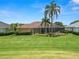 Expansive backyard with screened lanai, lush green lawn, and tropical palm trees at 2936 Grasslands Dr, Lakeland, FL 33803