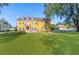Stately yellow three-story home with large lawn, balcony, dormer windows, and mature trees on a sunny day at 3020 Crews Lake Dr, Lakeland, FL 33813