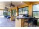 Covered outdoor kitchen with granite countertops, stainless steel appliances, and a bar area, perfect for entertaining at 3020 Crews Lake Dr, Lakeland, FL 33813
