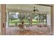 A screened lanai with brick pavers, ceiling fan, dining table, and wicker seating area with green grass view at 3176 Pearly Dr, Lakeland, FL 33812