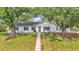Beautiful single-story home with mature trees, a white exterior, blue shutters, and a well-kept lawn at 4825 Foxrun, Lakeland, FL 33813