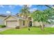Home exterior showcasing the well-kept lawn, tropical trees and attached two-car garage at 601 Peninsular Dr, Lakeland, FL 33813