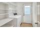 A well-lit laundry room with shelving, washer, dryer, and a door to the outside at 6065 Magpie Dr, Lakeland, FL 33809