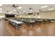 Spacious meeting room with many tables and chairs, ceiling fans, stage, and wood-look flooring at 6065 Magpie Dr, Lakeland, FL 33809