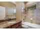A well-lit bathroom featuring a granite countertop, backsplash, and a shower-tub combination at 6527 Eagle Ridge Way, Lakeland, FL 33813