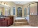 Bathroom with tiled floors, granite vanity, and tub with tiled surround at 6527 Eagle Ridge Way, Lakeland, FL 33813
