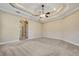 Spacious bedroom featuring neutral carpet and paint, tray ceilings, and an open doorway at 6527 Eagle Ridge Way, Lakeland, FL 33813