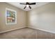 Cozy bedroom with soft carpeting, base trim, neutral colored walls, a ceiling fan, and a window overlooking the front yard at 6527 Eagle Ridge Way, Lakeland, FL 33813