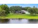 Expansive backyard with lush greenery, a serene lake view, and a screened-in lanai at 7016 Summit Cir, Winter Haven, FL 33884