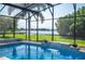 Relaxing pool with a waterfall feature, screened enclosure, and scenic views of the water at 7016 Summit Cir, Winter Haven, FL 33884