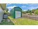 An exterior shot of a green storage building with a roll-up door in the backyard at 808 Austin Cir, Bartow, FL 33830