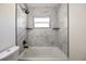 Bright bathroom with marble-style tiling surrounding a tub and a shower with black hardware at 3813 Surrey Dr, Orlando, FL 32812