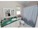 Bathroom with window, shower with decorative curtain, and green vanity with storage at 1130 Ewell Rd, Lakeland, FL 33811