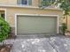 Two-car garage with a light green door and stone accents, showcasing the home's curb appeal at 143 Alfani St, Davenport, FL 33896