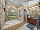Bathroom featuring a soaking tub, tiled walls, a vanity with brown cabinets, and a glass shower enclosure at 148 Melissa Trl, Auburndale, FL 33823