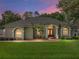 Home's exterior at dusk with manicured lawn, palm trees, and inviting arched entry at 148 Melissa Trl, Auburndale, FL 33823