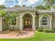 Home's front exterior with brick walkway, arched entry, palm trees and manicured lawn at 148 Melissa Trl, Auburndale, FL 33823