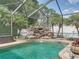 Screened-in pool boasts a rock waterfall feature, surrounded by a decorative stone patio at 148 Melissa Trl, Auburndale, FL 33823