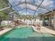 Lush screened-in pool area features a rock waterfall, patio, and palm tree landscaping at 148 Melissa Trl, Auburndale, FL 33823