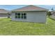 An image of the home's backyard featuring green lawn and the side of the house with a bank of windows at 1547 Cordgrass Way, Lakeland, FL 33813