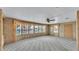 Living room featuring wood paneled walls, large windows, and neutral colored carpet at 1602 Tally Ho Dr, Lakeland, FL 33810