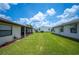 Lush green backyard between two houses under a blue sky at 1608 Colonnades N Cir, Lakeland, FL 33811