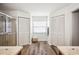 Bright ensuite bathroom with matching storage closets flanking a sunny window between the shower and vanity at 1608 Colonnades N Cir, Lakeland, FL 33811