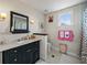 A charming bathroom features a black vanity, decorative mirror, and pink accents for a cheerful touch at 184 Melissa Trl, Auburndale, FL 33823
