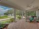 Relaxing screened-in porch with brick flooring and comfortable seating surrounded by lush landscaping at 184 Melissa Trl, Auburndale, FL 33823