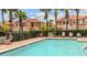 Community pool with lounge chairs, palm trees and terra cotta roofed buildings in the background at 1970 Michael Tiago Cir, Maitland, FL 32751