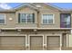 A tan townhouse showcasing three garage doors and a window with shutters at 2061 Crestdale Ln # 60, Lake Mary, FL 32746