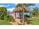 Tropical backyard with patio, Tiki hut and grill surrounded by lush greenery and tropical landscaping at 3052 Wood Duck Dr, Polk City, FL 33868