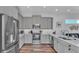 Modern kitchen with gray cabinets, stainless steel appliances, and hardwood floors, showcasing an open design at 3052 Wood Duck Dr, Polk City, FL 33868